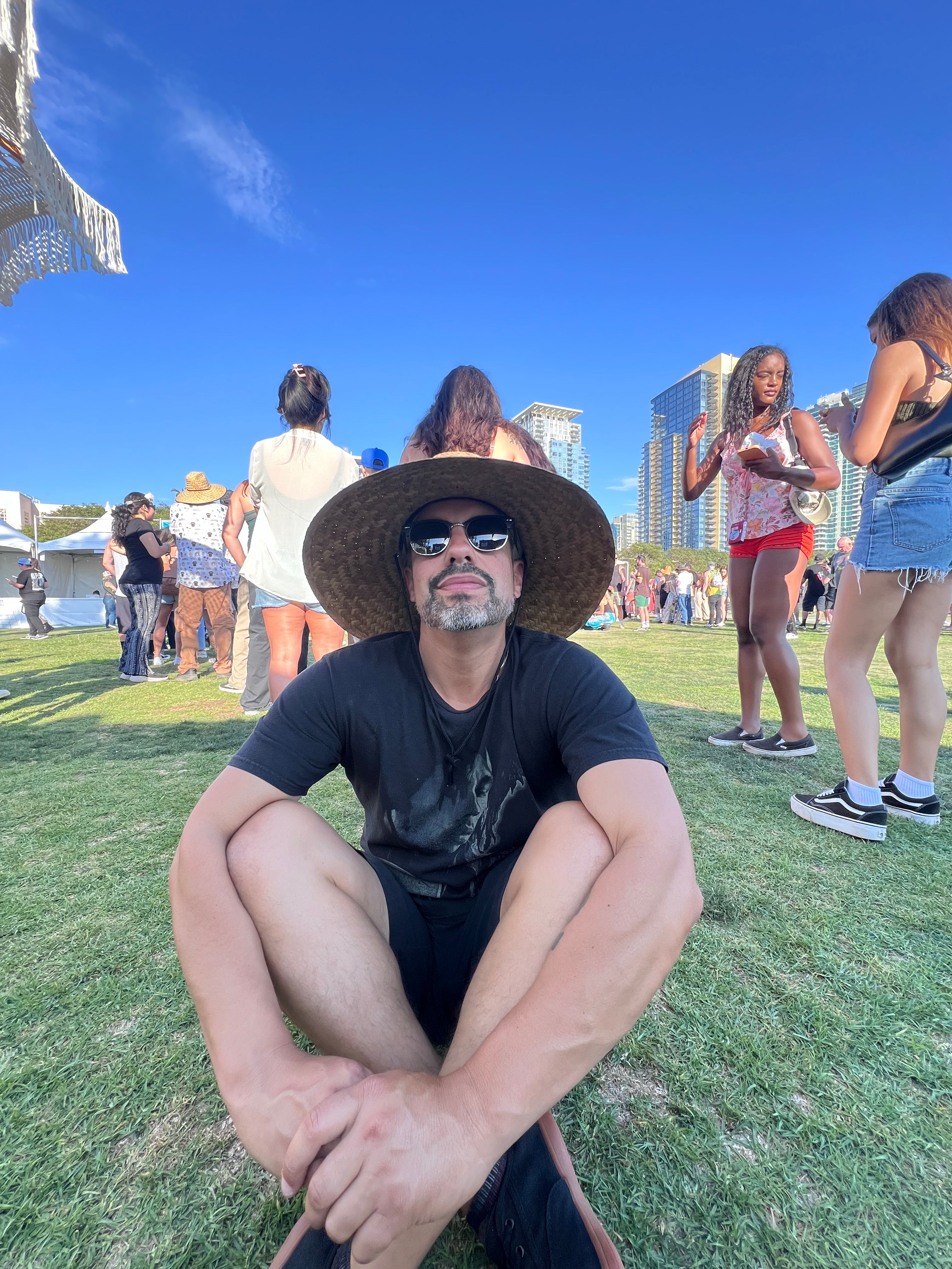 Sergio sitting on grass with a city skyline in the background
